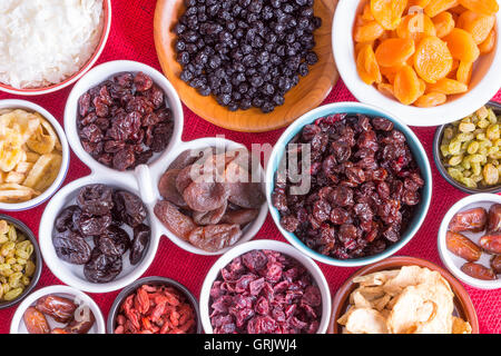 Arrière-plan coloré d'une variété de fruits secs dans des plats ronds sur toile rouge avec Apple, les baies de goji, d'abricot, de l'app Banque D'Images