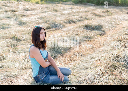 Pensive teen girl dans un champ avec str Banque D'Images