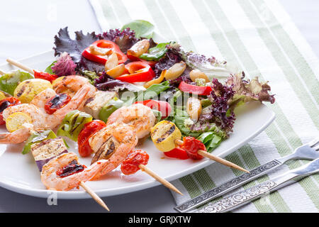 Servir sur une assiette de trois brochettes de crevettes gastronomique ou brochettes avec salade, tomate et piment doux , low angle Zoom sur Banque D'Images