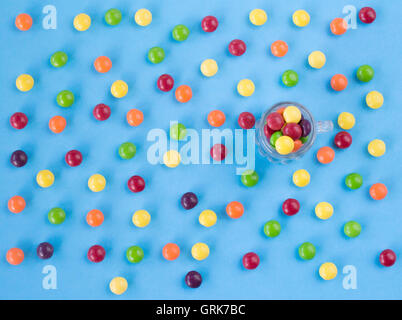 Bonbons colorés sur le fond bleu avec bol en verre et peu d'entre eux. Vue d'en haut. Mise à plat Banque D'Images