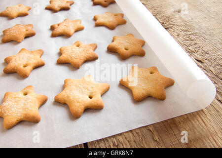 Gingerbread cookies faits maison (étoile) sur du papier sulfurisé et table en bois rustique Banque D'Images