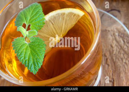 Thé au citron et de feuilles de menthe dans la cuvette transparente sur fond de bois rustique Banque D'Images