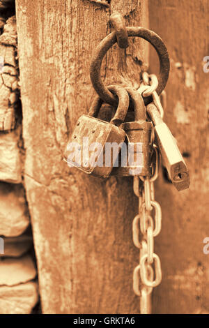 Vintage corrodés avec cadenas Chaîne sur une ancienne porte Contexte en sépia. Old Rusty cadenas sur une porte en bois. Banque D'Images