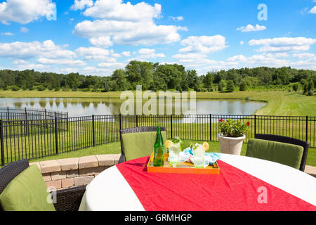 Verres d'eau glacée garnie avec de la Menthe et citron sur une table de jardin couvert dans un tissu rouge donnant sur une Banque D'Images