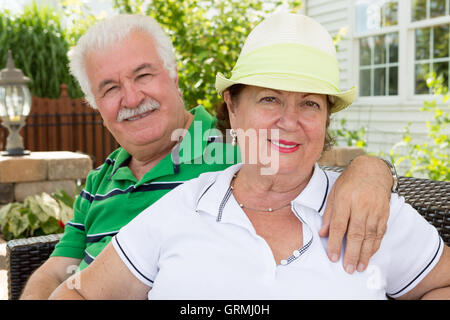 Joli couple heureux et en santé dans les bras sur une terrasse extérieure d'été en face de leur accueil chaleureux sourire à th Banque D'Images