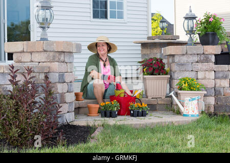 Heureux grand-mère âgée de style plantation dans son jardin de contentement assis sur les marches de son porche entouré par plant plants Banque D'Images