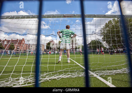 Football amateur, gardien de but vu à travers le filet de but, gazon artificiel Banque D'Images