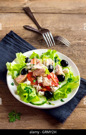 La salade de thon avec tomates, olives noires, le riz, la feta cheesse et verts sur fond de bois rustique Banque D'Images