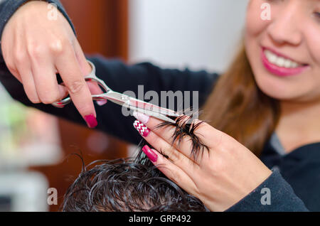 Smiling hairstylist faisant un grand homme coupe de cheveux avec des ciseaux Banque D'Images