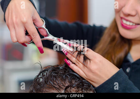 Smiling hairstylist faisant un grand homme coupe de cheveux avec des ciseaux Banque D'Images