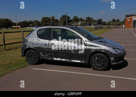 Un vieux battu salon de voiture en faisant une voiture parc ayant été peints sur tout y compris les fenêtres de peinture noire. Banque D'Images