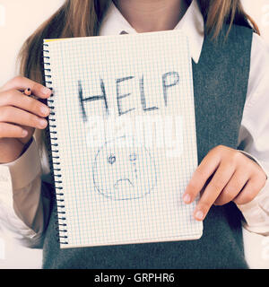 Une image couvrant les enjeux sociaux de la violence faite aux enfants, écoliers en uniforme que demander de l'aide par un message écrit disant aide avec Banque D'Images