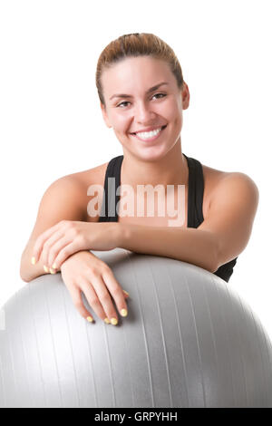 Fit woman sitting et tenant une balle Pilates au sol, isolé en blanc Banque D'Images