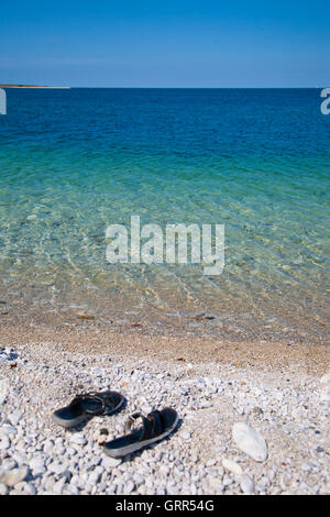 Paire de sandales sur une plage en pierre de galets Banque D'Images