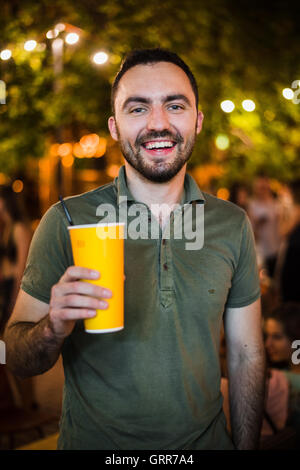 L'Homme barbu beau coctail potable ou de la bière en plein air au Café de la rue la nuit de la partie in park Banque D'Images