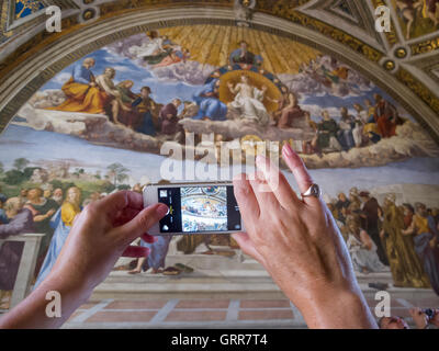 Un touriste dans la salle Raphaël au Vatican de la prise d'une photo sur un téléphone intelligent Banque D'Images