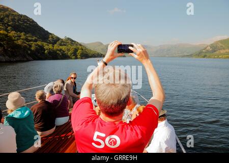 Les touristes appréciant une croisière et prenant des photos avec un téléphone intelligent à bord de l'arc d'Ullswater Steamers. Ullswater, Penrith. Banque D'Images