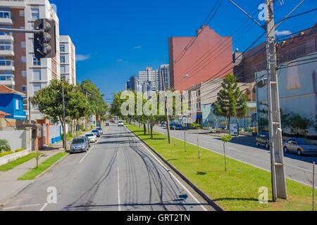 CURITIBA, BRÉSIL - 12 MAI 2016 : long rue vide avec quelques autos garées sur les côtés et quelques arbres sur le trottoir Banque D'Images