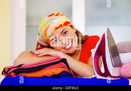 Charmante Jeune femme portant le foulard coloré resting head on pile de vêtements, blanchisserie repassage ménage concept Banque D'Images