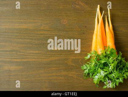 Botte de carottes fraîches avec des feuilles vertes sur fond de bois Banque D'Images