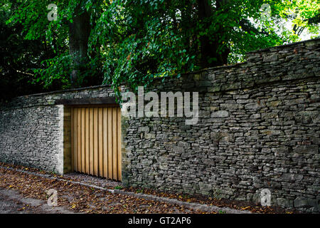 Simple porte en bois dans un mur de pierre comme une porte de garage à l'entrée d'une propriété privée dans les bois. Banque D'Images