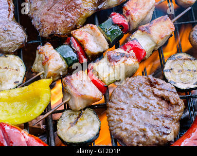 Un assortiment de légumes avec de la viande la cuisson sur le gril avec des flammes. Banque D'Images