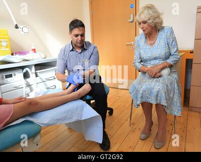 Le Dr Tariq Khan (à gauche) examine un jeune patient à côté de la duchesse de Cornouailles, Patron de l'ordre de la podologie, lors de sa visite au Royal London Hospital pour la médecine intégrée dans le centre de Londres où elle a rencontré les podiatres et les patients. Banque D'Images