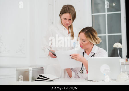 Doctor and nurse looking at documents in medical office Banque D'Images