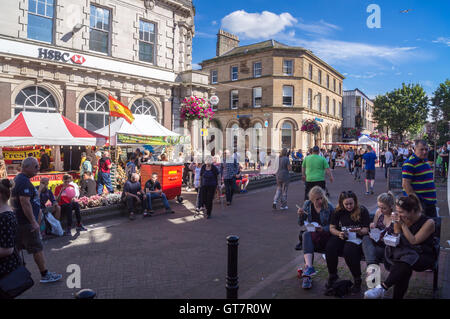 Un groupe de jeunes femmes eating Chinese food sur un banc à l'extérieur de HSBC et Barclays Bank Market Place, Carlisle, Cumbria, Angleterre en été Banque D'Images