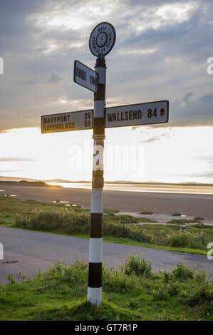 Inscrivez-Fingerpost affichage des distances à Wallsend, Maryport et Rome, Solway Firth au coucher du soleil, Bowness-on Solway, Cumbria, Angleterre Banque D'Images