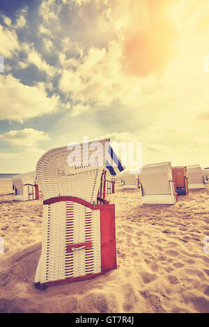 Tons Vintage chaises de plage en osier à capuchon sur une plage au coucher du soleil, vacances d'concept. Banque D'Images