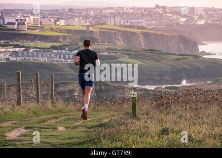 Un homme court le long du chemin côtier du sud-ouest vers Newquay en Cornouailles. Banque D'Images