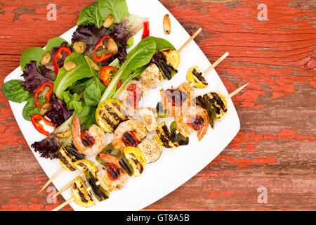 Brochettes de crevettes gastronomique appétissant servi sur plaque blanche avec légumes et épices sur le dessus d'une table en bois rustique, capturé le hig Banque D'Images