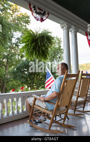 L'âge moyen heureux homme assis sur un fauteuil à bascule en bois sur la terrasse et l'affichage de la nature détente tout en profitant de la 4e jour o Banque D'Images