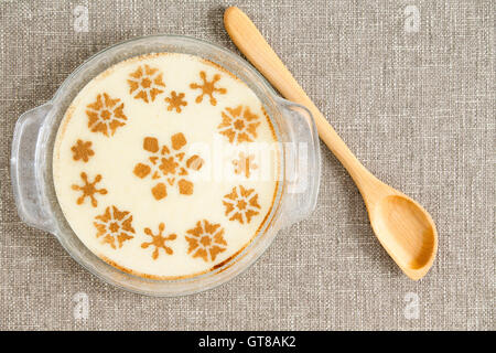 Vue aérienne d'une table gastronomique savoureux dessert semoule lactée sur bol placé au-dessus d'un tissu gris avec louche en bois sur le côté. Banque D'Images