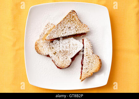 Vue aérienne de délicieux toasts de pain avec de la confiture de fraises sucrées garniture sur plaque blanche pour le petit déjeuner. Jaune isolé sur Backg Banque D'Images