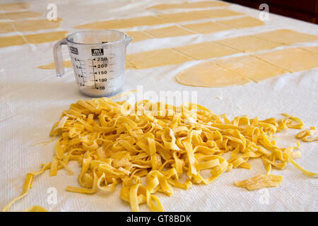 Tas de pâtes fraîches maison pâtes préparées avec de la semoule de blé dur et de pâte sur un comptoir de cuisine avec des feuilles de uncut d Banque D'Images