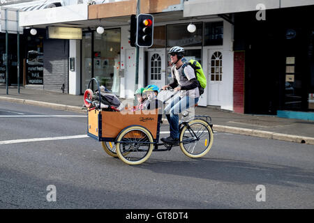 Les pédales d'un homme ses enfants sur un vélo dans la banlieue de Sydney Newtown. Banque D'Images