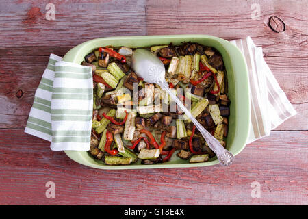 Frais délicieux légumes rôtis dans un plat à four avec un chiffon de cuisine Cuillère et servir sur une table en bois, high angle vie Banque D'Images