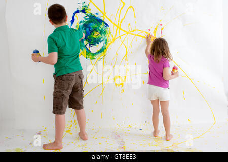 Deux jeunes enfants, un garçon de dix ans et trois ans, fille, Freehand peinture sur un mur avec les peintures acryliques colorés creatin Banque D'Images