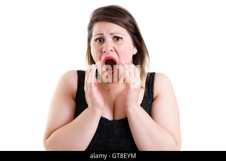 Femme avec des yeux effrayés et dilatées élever ses mains à sa bouche dans la terreur comme elle hurle, isolated on white Banque D'Images