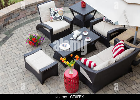 Portrait de l'ensemble Patio haut de gamme, mobilier de luxe en osier foncé avec de confortables coussins sur patio extérieur en pierre des riches Banque D'Images