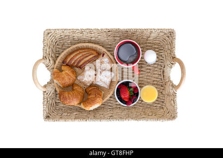 Portrait de l'Osier plateau de petit-déjeuner avec assortiment de pains et petits fruits, café, jus et oeuf dur sur blanc Banque D'Images