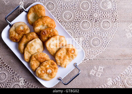 Le bac de Turc pisi halka frites traditionnelles, ou des crumpets frite, servi sur une vieille table avec une nappe en dentelle et copier sp Banque D'Images