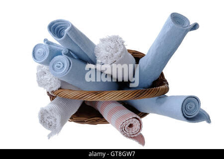 Portrait d'un assortiment de nouveaux tapis roulés lavés dans un panier en bois isolé sur un fond blanc. Banque D'Images