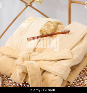 Robe pliée avec du savon et une brosse à dents sur la chaise en osier Banque D'Images