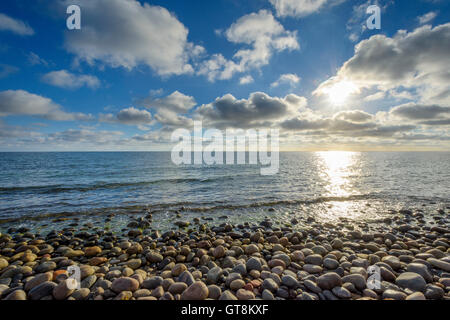 Ciel avec nuages et soleil sur la plage de galets, l'été, Sealands Odde, Odsherred,, la mer Baltique, la Nouvelle-Zélande, le Danemark Banque D'Images