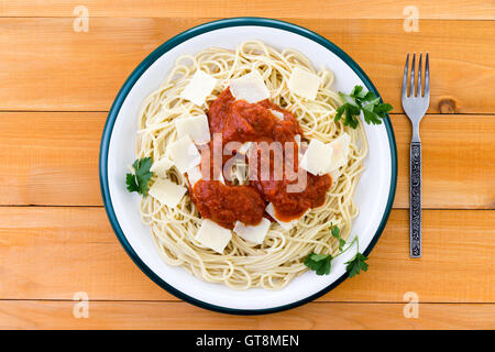 Vue du haut vers le bas sur le plat de pâtes et nouilles Spaghetti garnie de fromage "Grana Padano" bits, persil italien et de sauce rouge brow Banque D'Images