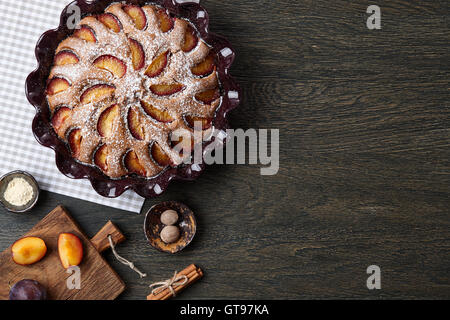 Tarte aux prunes et les ingrédients sur une table en bois foncé Banque D'Images