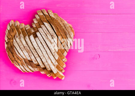 Vue d'en haut de et les tranches de pain en forme de coeur sur fond de panneaux de bois peint en rose avec copie espace pour valenti Banque D'Images